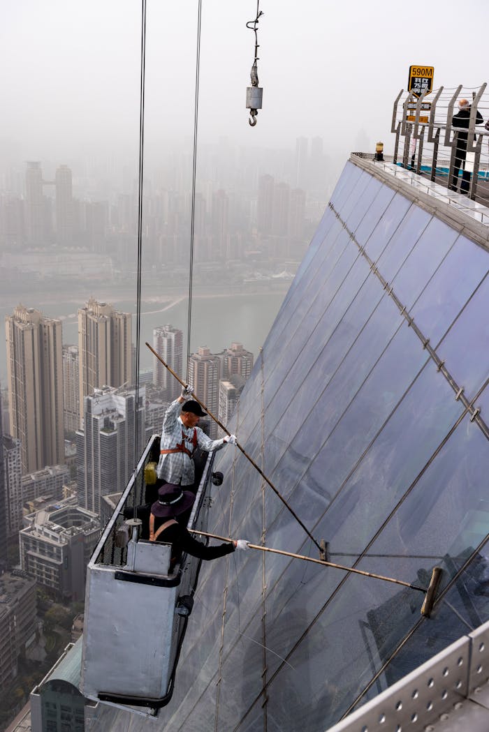 Two workers clean skyscraper windows overlooking a bustling city skyline, demonstrating urban maintenance.